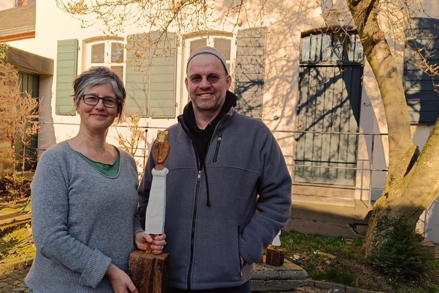 Das Foto zeigt die Geschäftsführerin des Hildegardis-Vereins Birgit Mock mit dem Künstler Ralf Knoblauch. Zwischen ihnen halten sie eine Königinnenfigur.